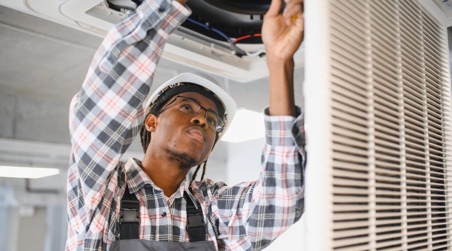 HVAC technician wearing protective gloves and repairing an outdoor AC unit, focused on ensuring reliable heating and cooling service.