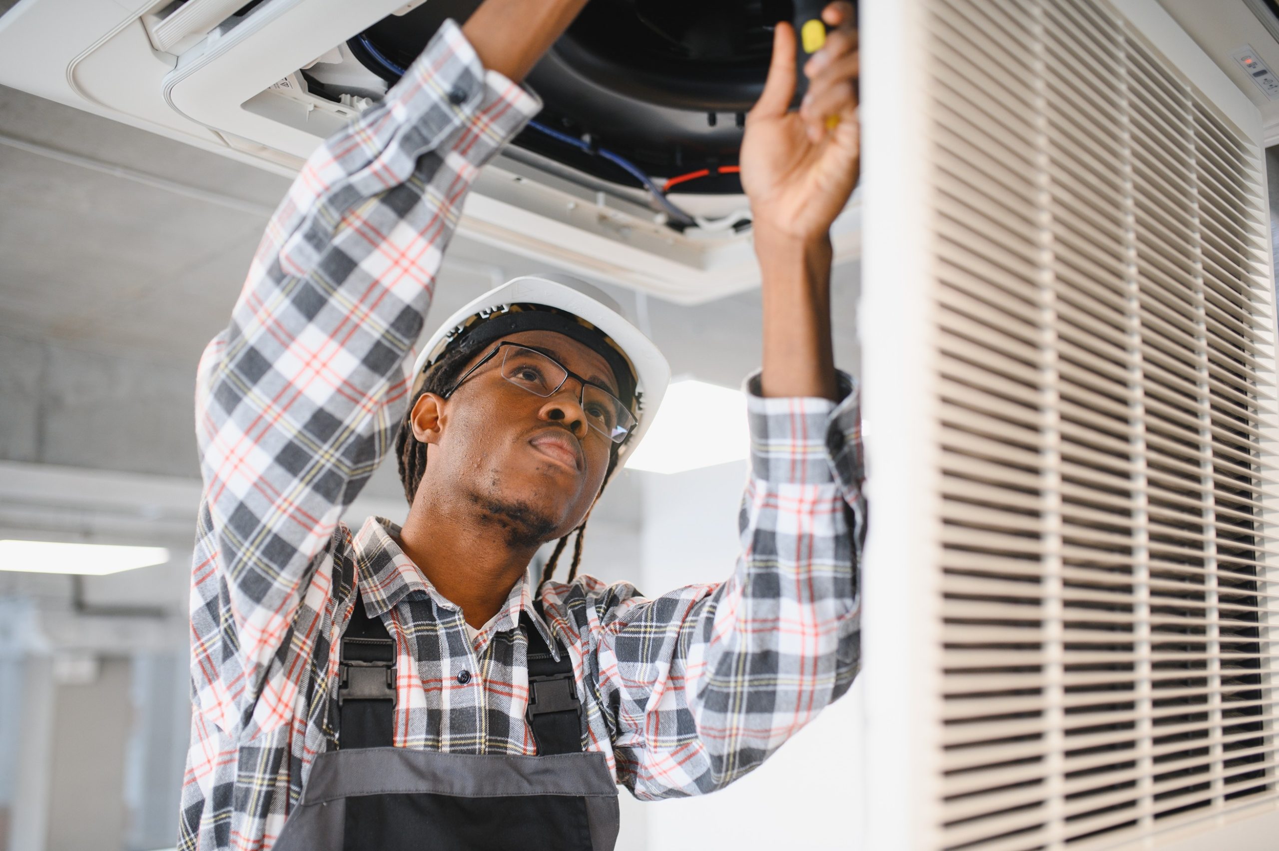 HVAC technician wearing protective gloves and repairing an outdoor AC unit, focused on ensuring reliable heating and cooling service.