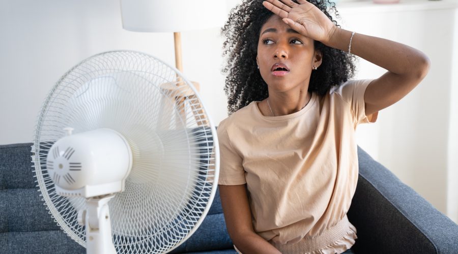 Homeowner sweating indoors using fan during AC breakdown, emergency air conditioner repair Frederick County