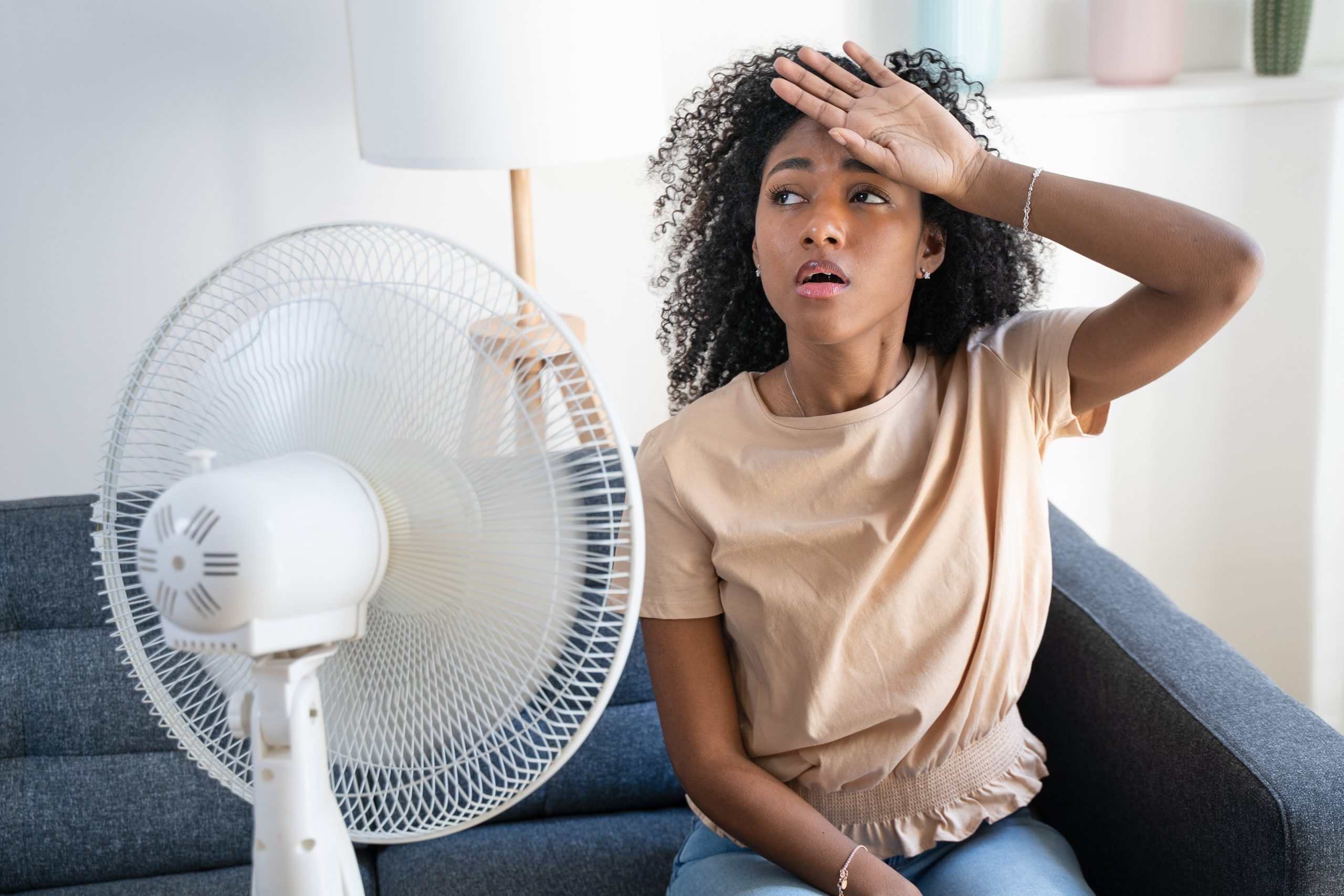 Homeowner sweating indoors using fan during AC breakdown, emergency air conditioner repair Frederick County