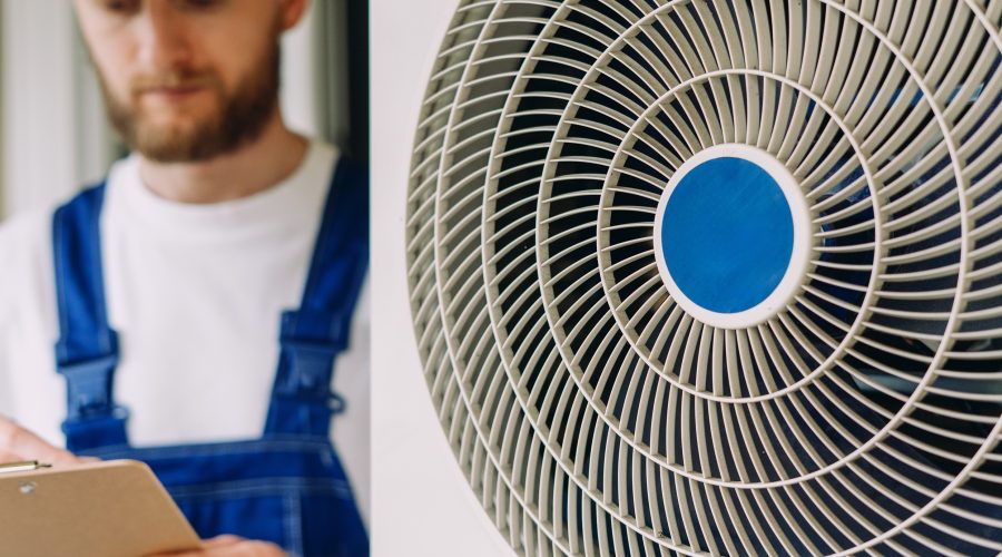 HVAC technician inspecting residential air conditioner unit during maintenance service.