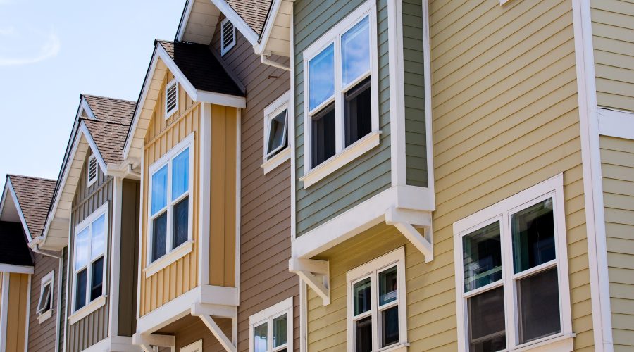 Row of modern townhomes in Columbia, MD under bright sunlight, illustrating heat buildup and need for attic fan installation.