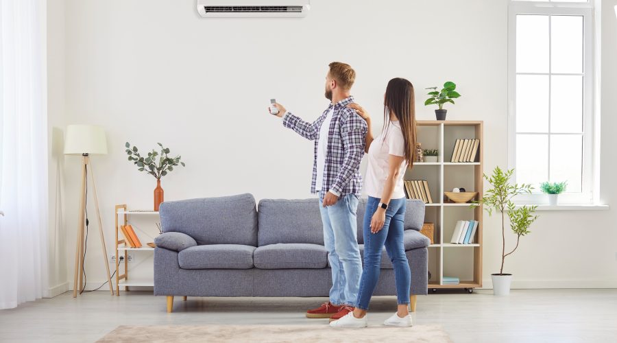 Ductless mini split installation Pasadena MD couple adjusting wall mounted air conditioner with remote.