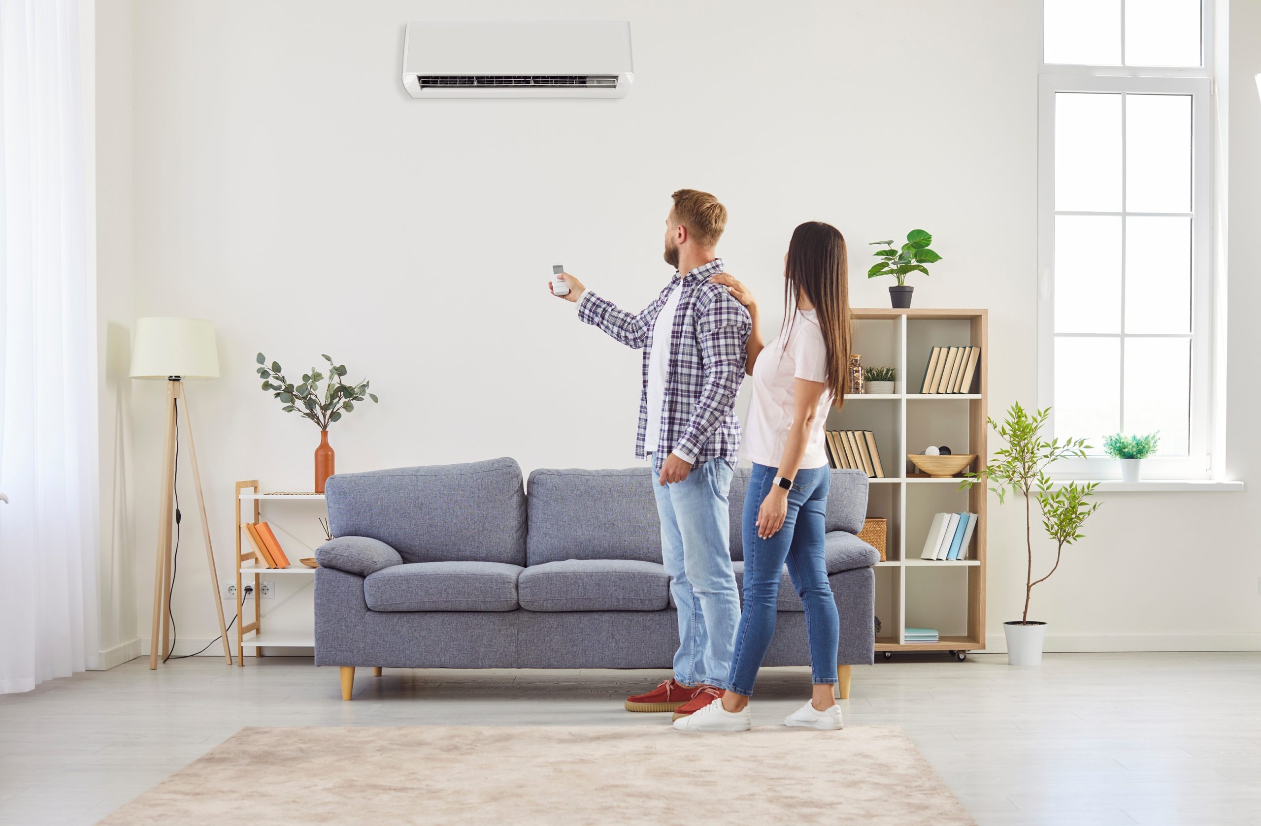 Ductless mini split installation Pasadena MD couple adjusting wall mounted air conditioner with remote.