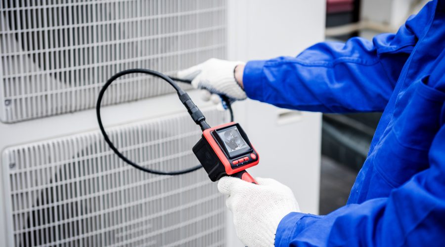 HVAC technician diagnosing an outdoor air conditioning system.