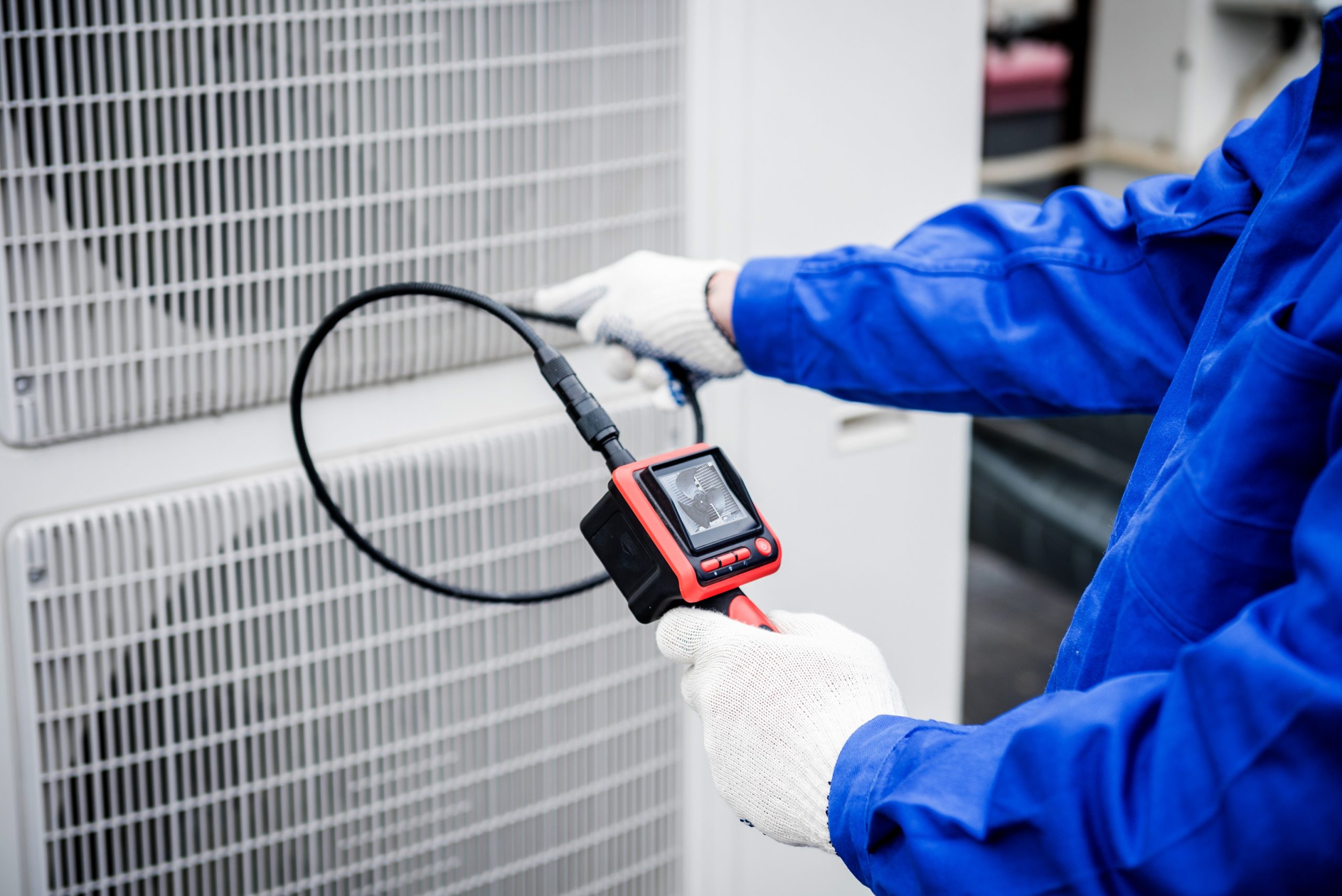 HVAC technician diagnosing an outdoor air conditioning system.