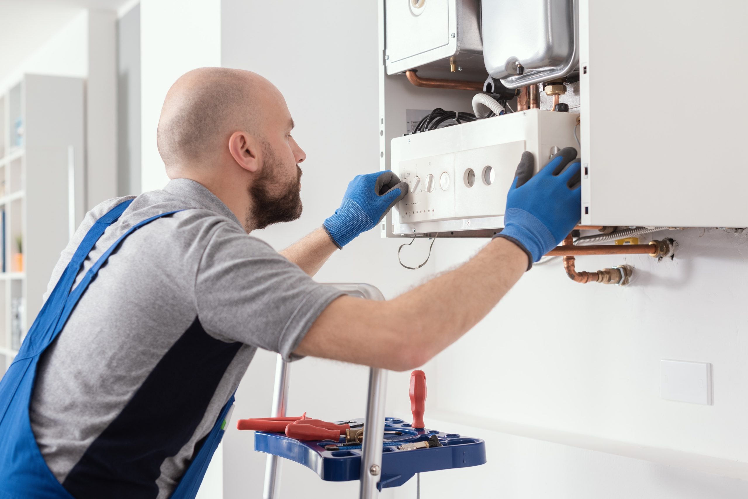 HVAC technician working on a residential boiler during heating system maintenance